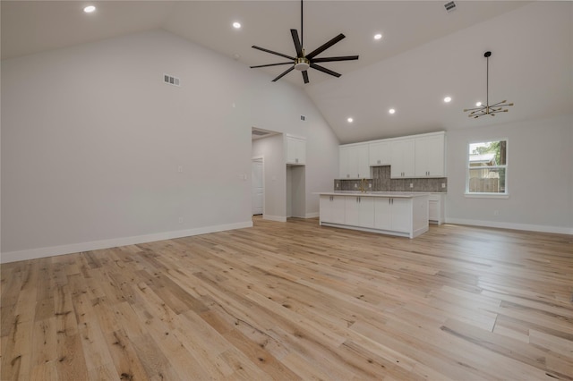 unfurnished living room with recessed lighting, high vaulted ceiling, light wood-type flooring, and visible vents