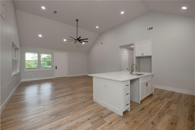 kitchen featuring white cabinets, open floor plan, visible vents, and a sink