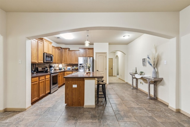 1925 Bridgeport Dr, Providence Village, TX 76227 - kitchen featuring a sink, dark countertops, baseboards, arched walkways, and appliances with stainless steel finishes