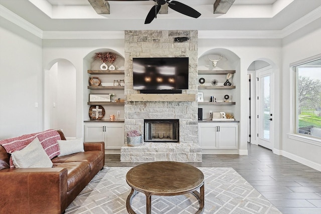 living area with ornamental molding, a fireplace, a ceiling fan, and wood finished floors