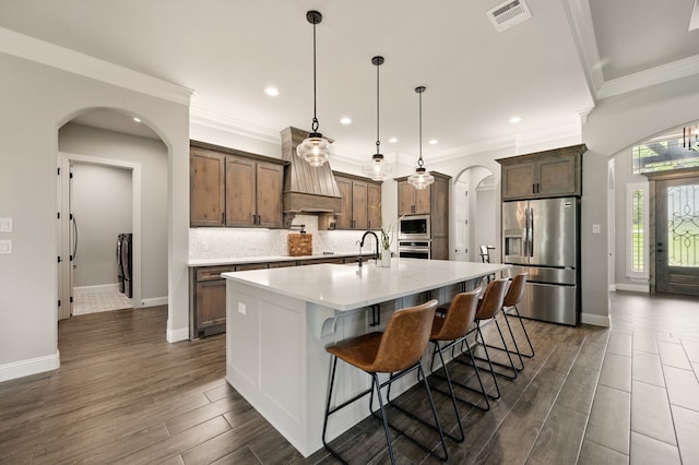 317 Wayward Spur, Springtown, TX 76082 - kitchen with appliances with stainless steel finishes, arched walkways, light countertops, tasteful backsplash, and a large island with sink