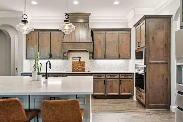 317 Wayward Spur, Springtown, TX 76082 - kitchen featuring appliances with stainless steel finishes, ornamental molding, pendant lighting, a sink, and arched walkways