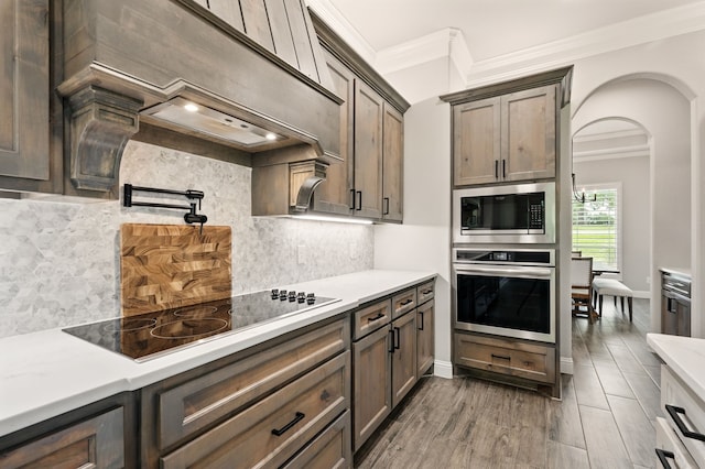 317 Wayward Spur, Springtown, TX 76082 - kitchen with stainless steel appliances, ornamental molding, decorative backsplash, arched walkways, and wood finished floors