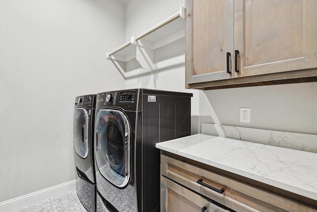 clothes washing area with baseboards, washer and clothes dryer, and cabinet space