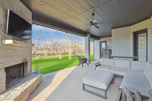 view of patio / terrace with a ceiling fan and an outdoor living space with a fireplace