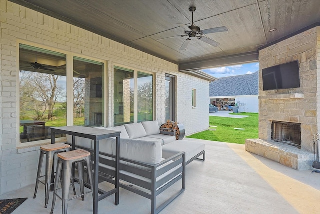 view of patio / terrace featuring a ceiling fan and an outdoor living space with a fireplace