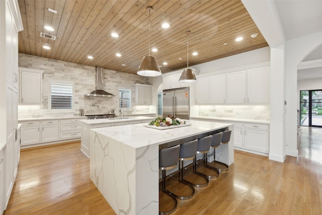 kitchen with visible vents, a kitchen island, wall chimney exhaust hood, wooden ceiling, and appliances with stainless steel finishes