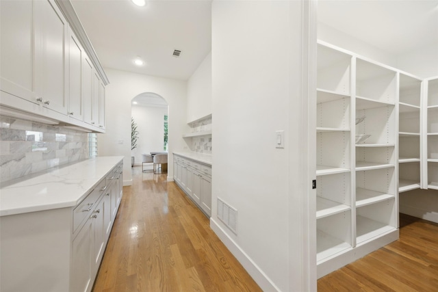 interior space with light wood-type flooring, arched walkways, visible vents, and recessed lighting