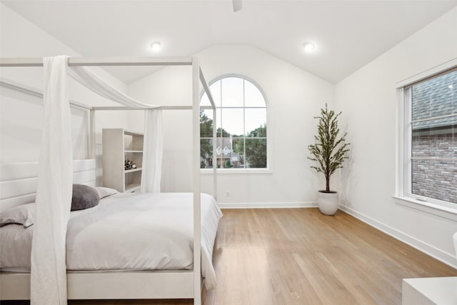 bedroom featuring baseboards, wood finished floors, and lofted ceiling