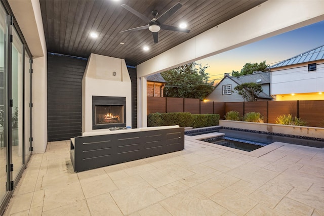 view of swimming pool featuring a hot tub, ceiling fan, a fenced backyard, a large fireplace, and a patio