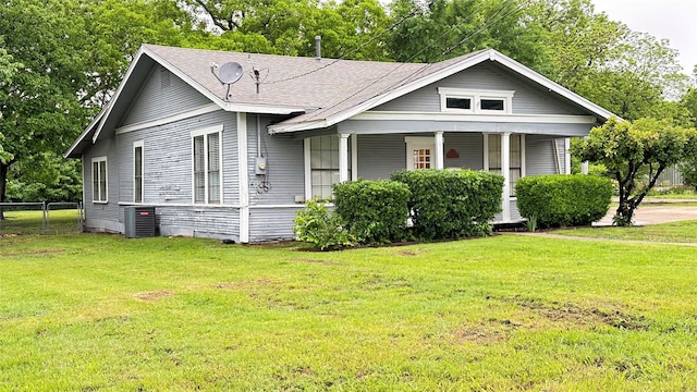 view of front facade featuring fence, covered porch, central AC, and a front lawn