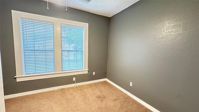 carpeted spare room with a textured ceiling and baseboards