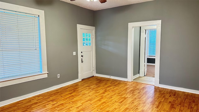 entrance foyer featuring baseboards, a textured ceiling, ceiling fan, and light wood-style flooring
