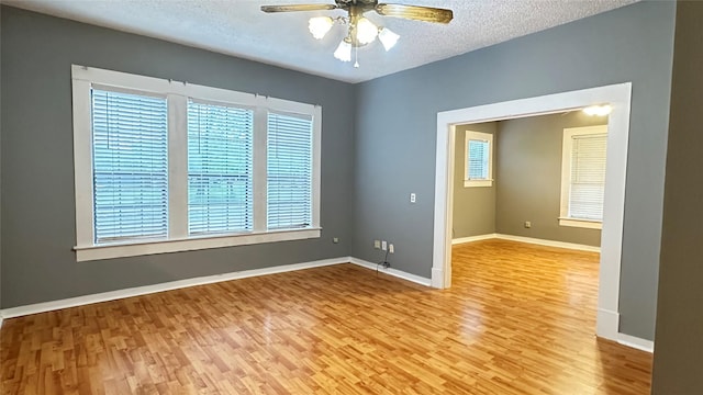 empty room featuring baseboards, a textured ceiling, ceiling fan, and wood finished floors