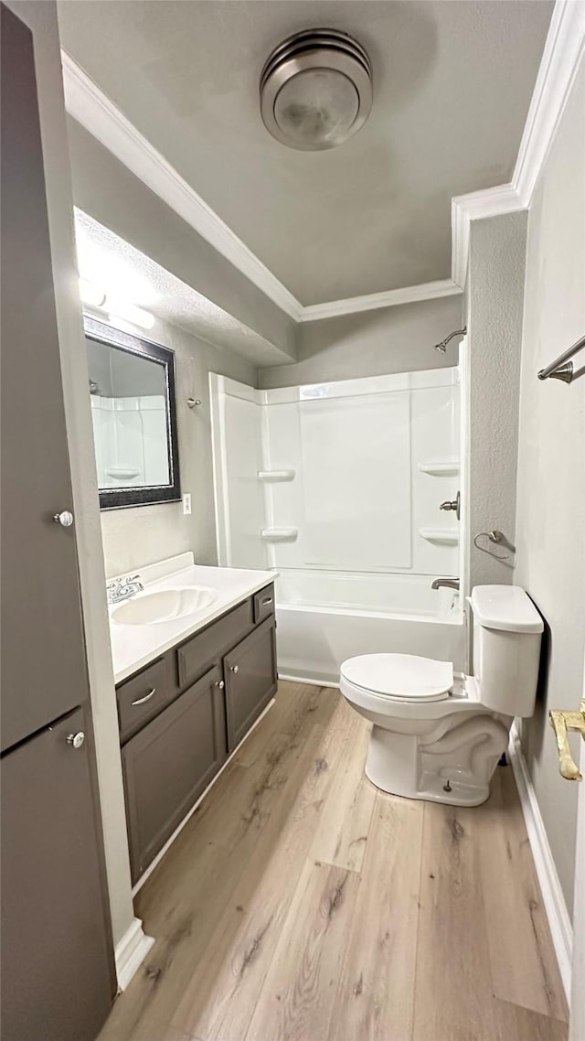 bathroom with vanity, ornamental molding, wood finished floors, toilet, and  shower combination