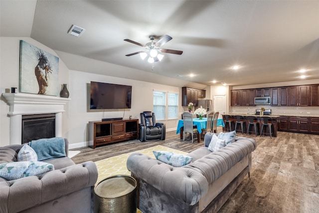 439 Tommie Lillian Ln, Celina, TX 75009 - living room featuring light wood-style flooring, visible vents, baseboards, ceiling fan, and a glass covered fireplace