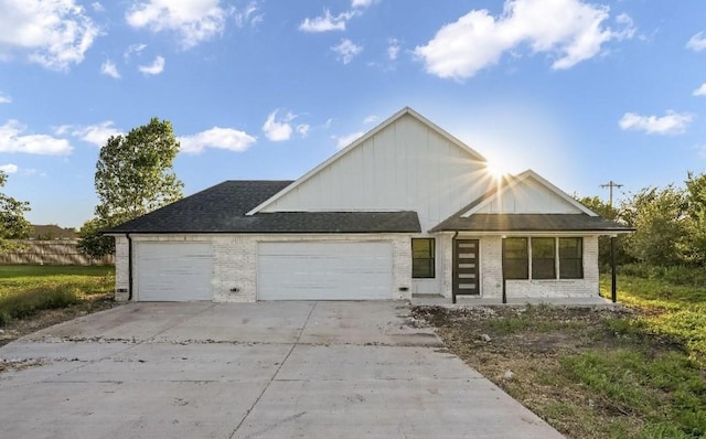 view of front of house with brick siding, an attached garage, board and batten siding, and driveway