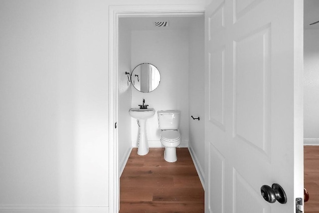 bathroom with toilet, baseboards, visible vents, and wood finished floors