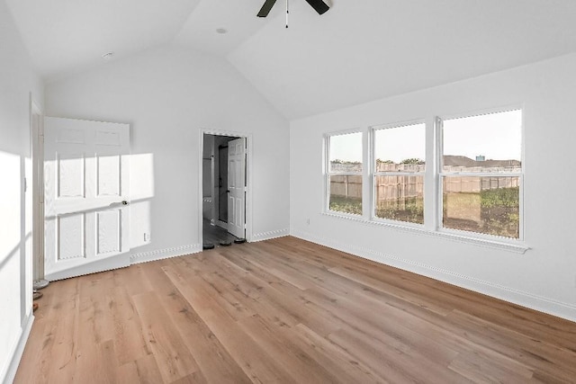 unfurnished bedroom featuring lofted ceiling, baseboards, ensuite bathroom, a ceiling fan, and light wood-style flooring