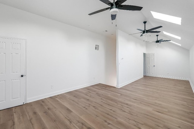 additional living space featuring vaulted ceiling with skylight, baseboards, light wood-style floors, and a ceiling fan