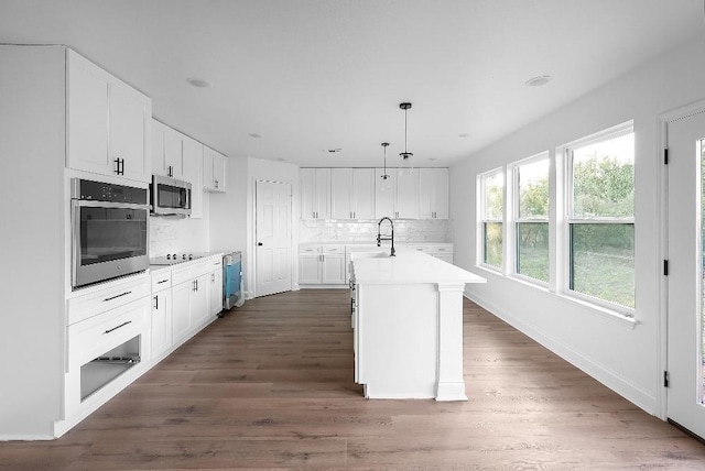 kitchen with white cabinets, appliances with stainless steel finishes, a sink, light countertops, and decorative backsplash