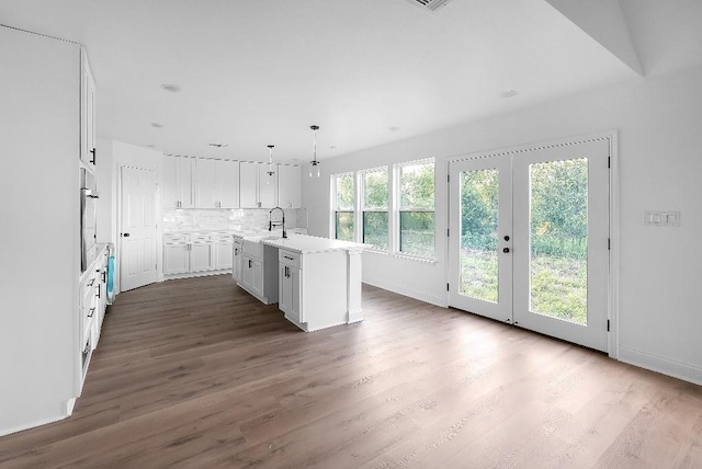 kitchen featuring dark wood-style flooring, tasteful backsplash, light countertops, a sink, and white cabinetry