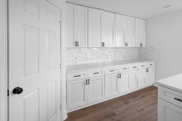kitchen featuring light countertops, backsplash, white cabinets, and dark wood-style floors