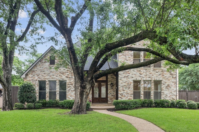 view of front of house with brick siding, fence, french doors, and a front yard