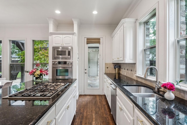kitchen featuring backsplash, a sink, dark stone countertops, stainless steel appliances, and white cabinetry