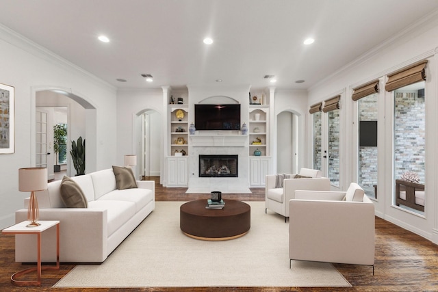 living room with arched walkways, ornamental molding, recessed lighting, and wood finished floors