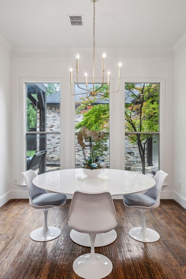 dining space featuring crown molding, a notable chandelier, baseboards, wood finished floors, and visible vents