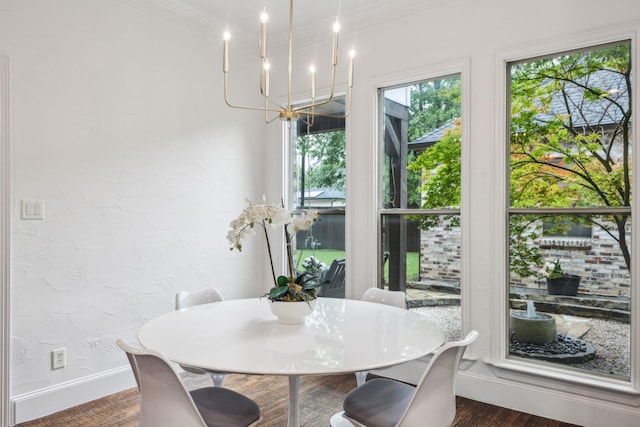 dining space featuring dark wood-type flooring, ornamental molding, baseboards, and a notable chandelier