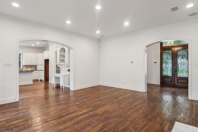 unfurnished living room featuring visible vents, crown molding, dark wood-style floors, french doors, and arched walkways