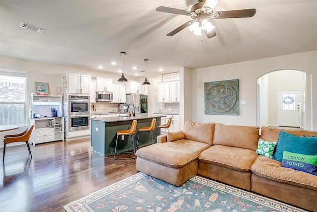 living room featuring arched walkways, a ceiling fan, recessed lighting, wood finished floors, and visible vents