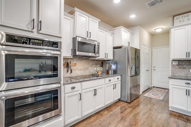 kitchen with visible vents, stone counters, white cabinets, light wood-style flooring, and appliances with stainless steel finishes