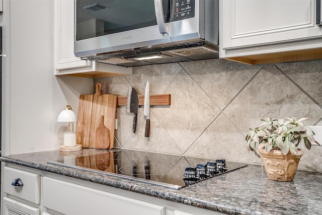interior details with white cabinetry, stainless steel microwave, black electric stovetop, and tasteful backsplash