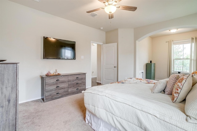 bedroom with a ceiling fan, visible vents, arched walkways, baseboards, and light carpet