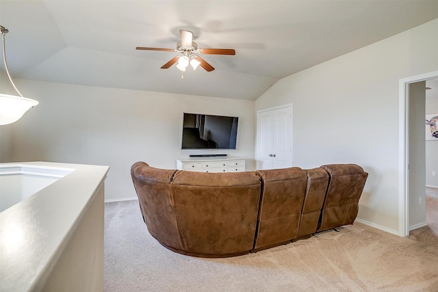living room featuring ceiling fan, light colored carpet, baseboards, and vaulted ceiling