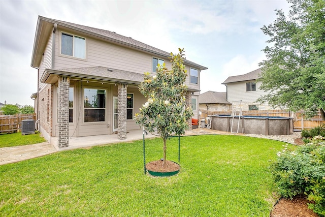 back of property with a fenced backyard, a fenced in pool, cooling unit, a patio, and a yard