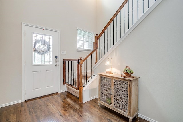 foyer entrance with baseboards, dark wood finished floors, stairway, and a towering ceiling