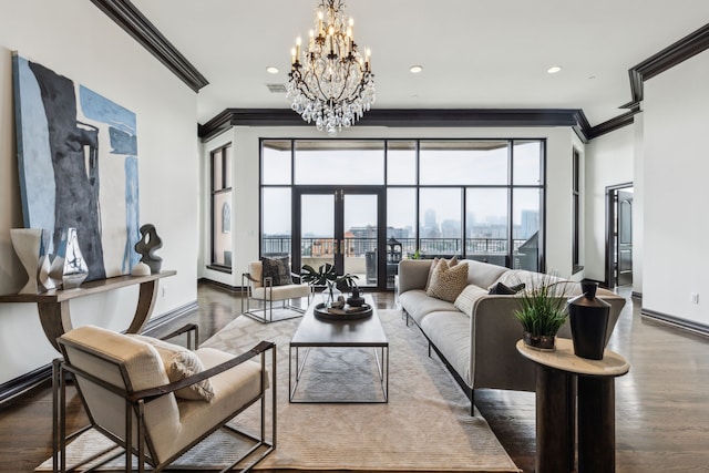 living area featuring plenty of natural light, crown molding, wood finished floors, baseboards, and a notable chandelier