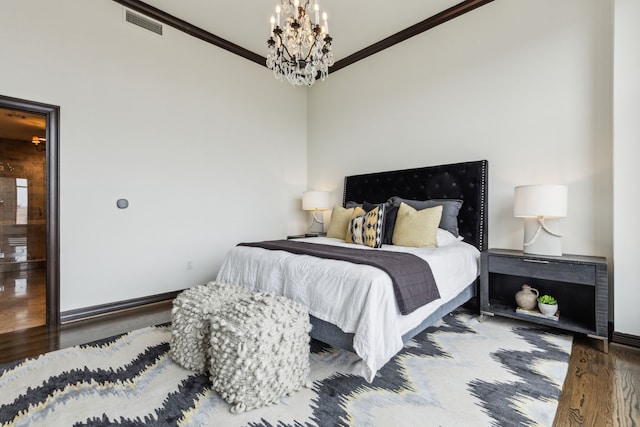 bedroom featuring visible vents, crown molding, wood finished floors, baseboards, and an inviting chandelier