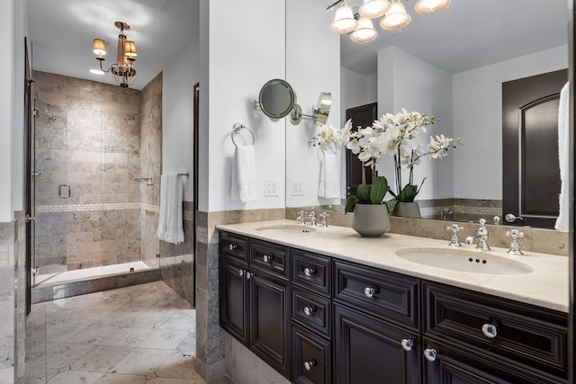 bathroom featuring double vanity, a notable chandelier, a sink, and a stall shower