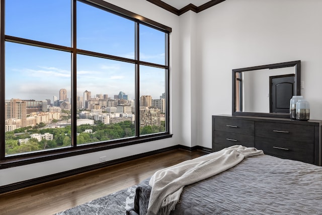 bedroom featuring a view of city, dark wood-style flooring, baseboards, and ornamental molding