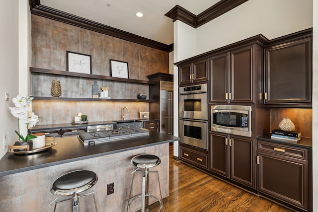 kitchen with stainless steel appliances, dark countertops, ornamental molding, and dark brown cabinets