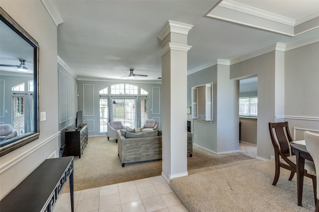 living area featuring crown molding, ceiling fan, light carpet, baseboards, and ornate columns