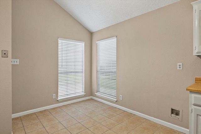 unfurnished room featuring baseboards, light tile patterned floors, vaulted ceiling, and a healthy amount of sunlight