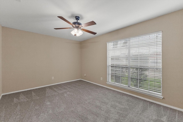 carpeted spare room with ceiling fan and baseboards
