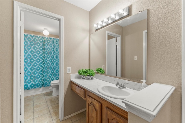 bathroom featuring tile patterned flooring, a textured wall, toilet, and vanity