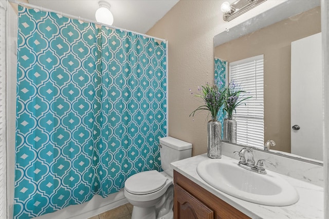 bathroom featuring vanity, tile patterned floors, a textured wall, and toilet